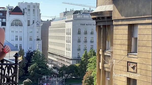 A woman undresses on a balcony in the city center. Public flashing.