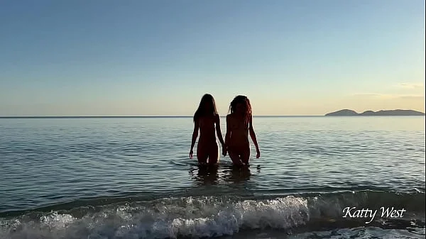Two naked beauties swim in the sea at dawn